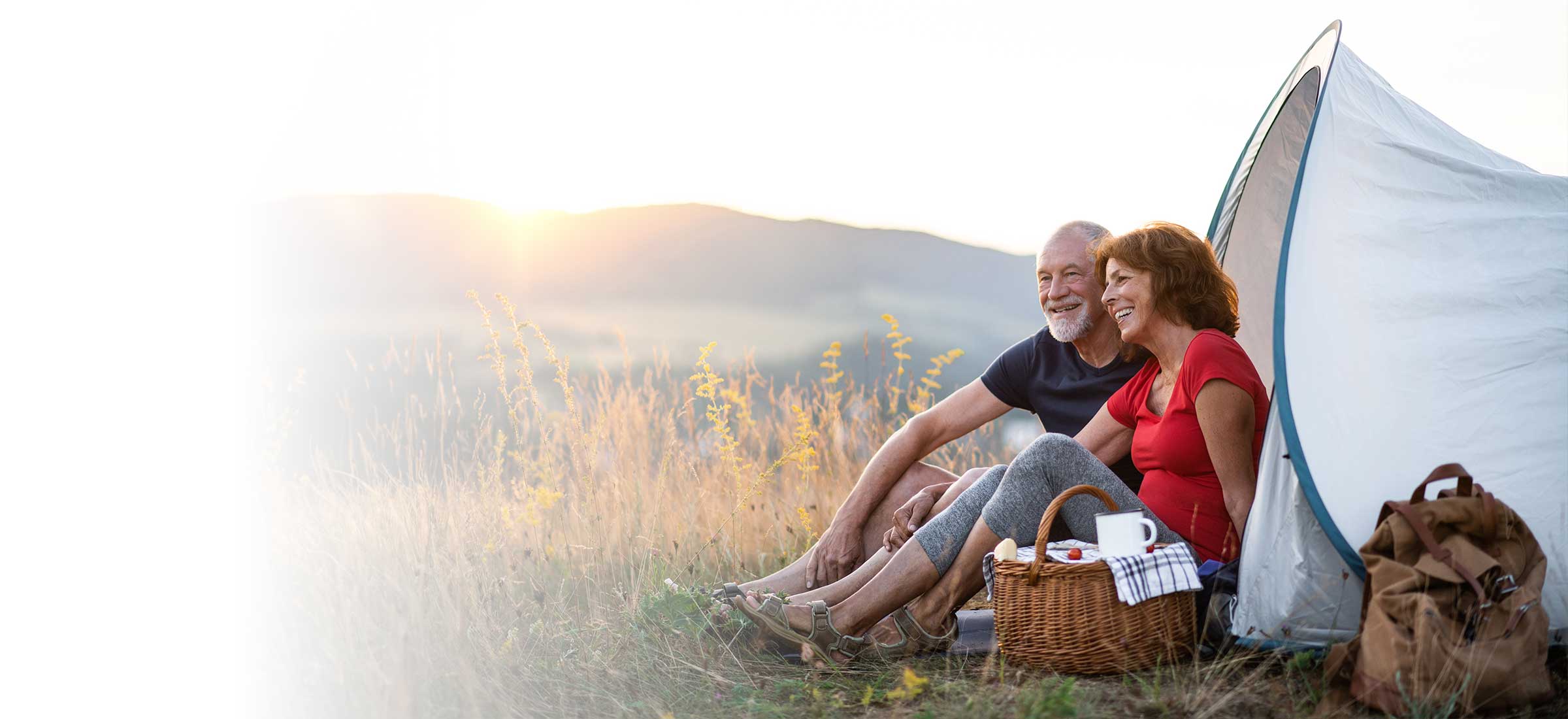 A couple sits outside their tent while camping.