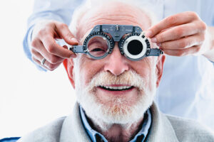 Portrait of a happy mature male patient undergoing vision check with special ophthalmic glasses.
