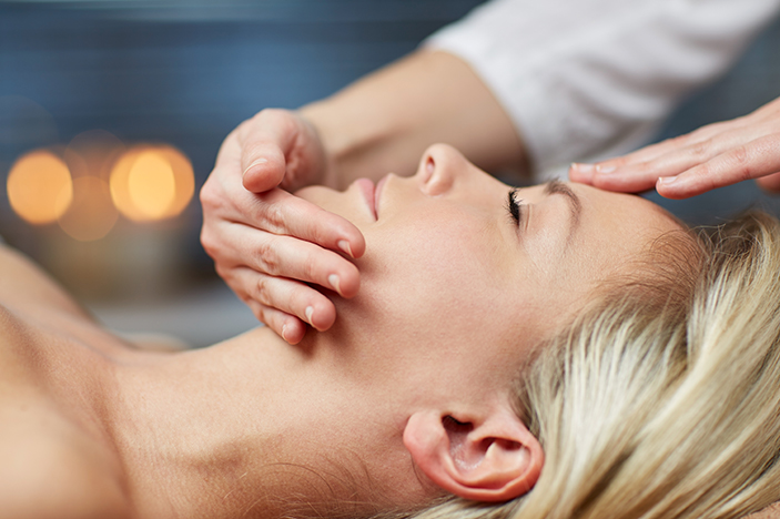 A woman's face is examined by a dermatologist in a medical office