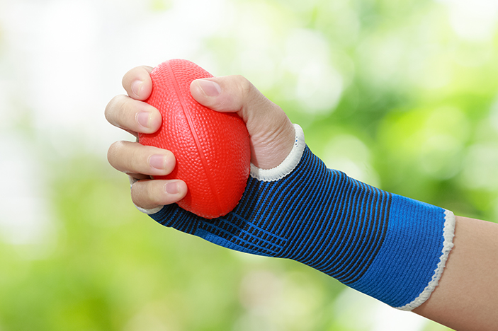 A person wearing a wrist splint holds a squeeze ball