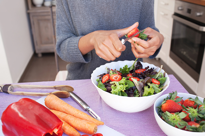 Woman makes salad with foods that help with cancer treatment and recovery