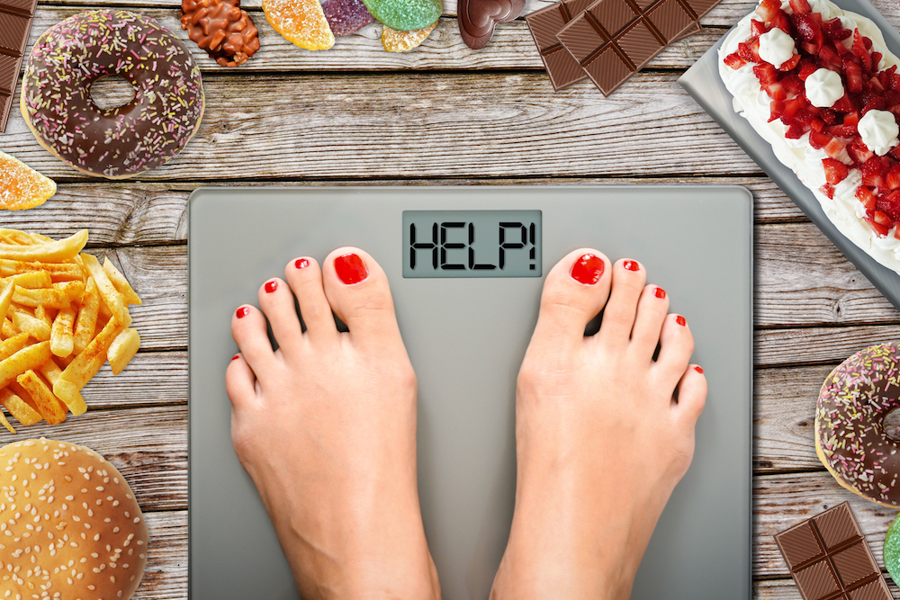 A woman stands on the scale, which reads, Help!