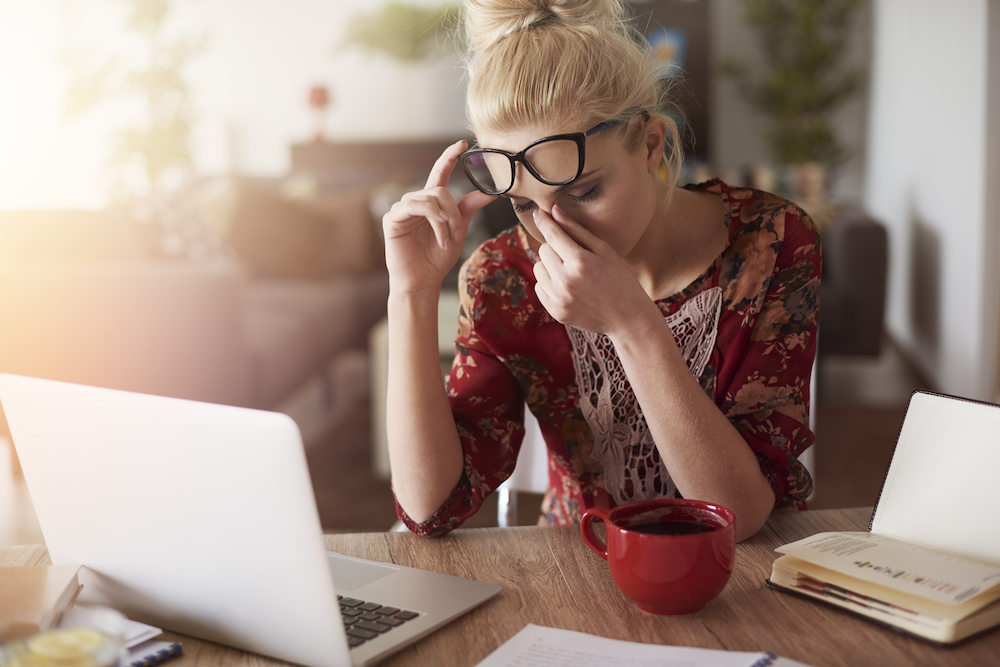 A woman working on a computer experiences a headache