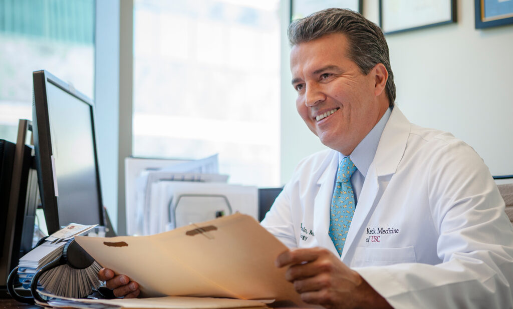 Dr. Sotelo, a provider at Keck Medicine of USC, sits while reviewing a file