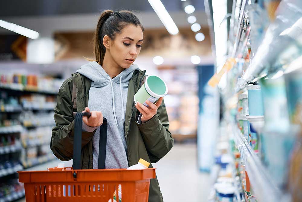 Woman reading a nutrition label while shopping at the grocery store