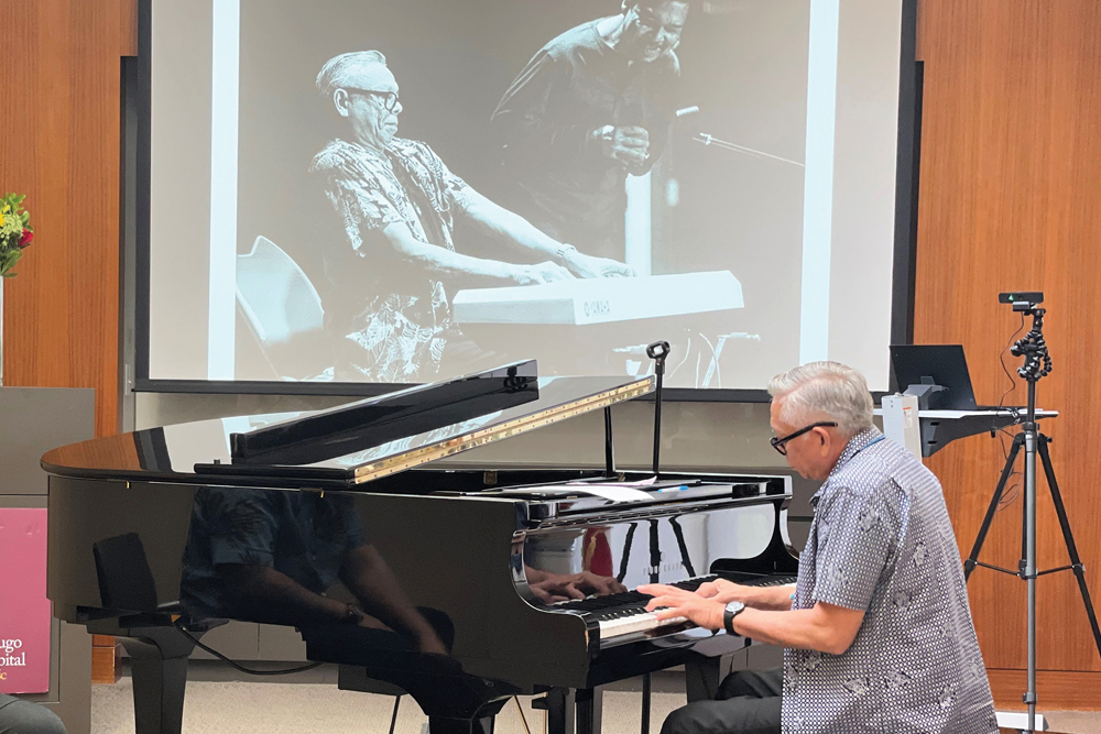 Prostate cancer patient Patrick Palomo plays piano in front of a projected image of himself playing the piano