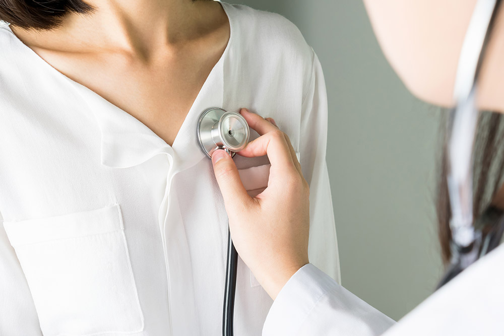 A doctor holds a stethoscope to a woman’s chest