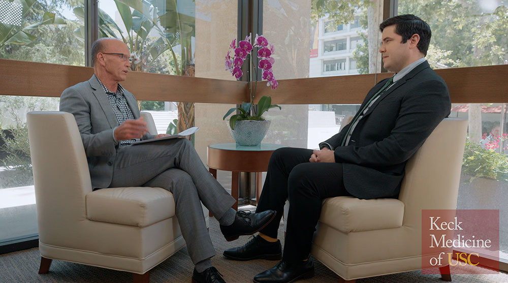 two men, Rod Hanners and Roberto Travieso, sit across from each other in an office building