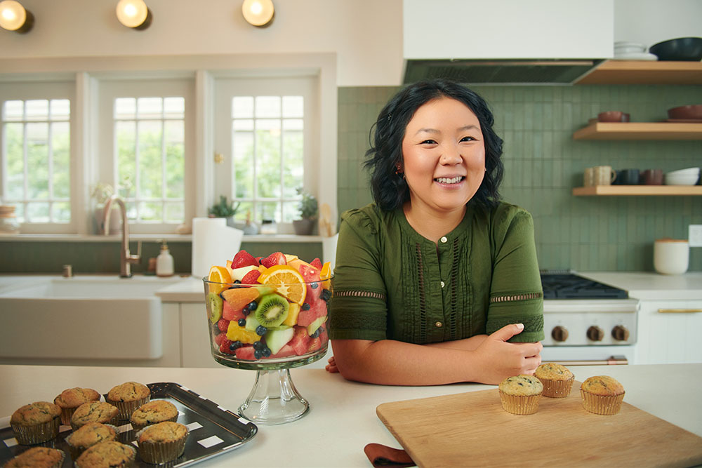 Melody LaTorre, a brain tumor survivor, sits in a Pasadena kitchen next to a bowl of fruit and a tray of muffins