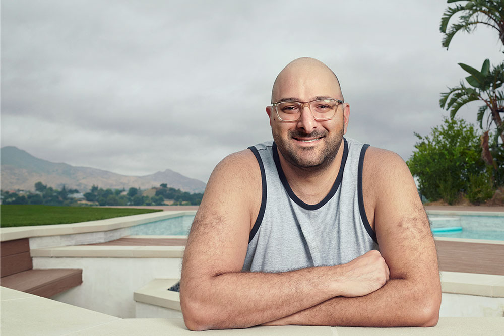 Testicular cancer survivor Cameron Khani folds his arms across his chest and smiles in a backyard in Agoura Hills