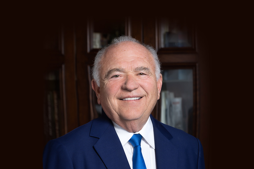 CEO and cancer survivor Joe Czyzyk smiles in a blue suit and tie for a headshot portrait