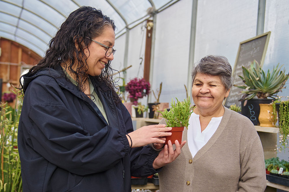 Margarita Gonzalez holds a potted plant for her mother Felicitas to appreciate