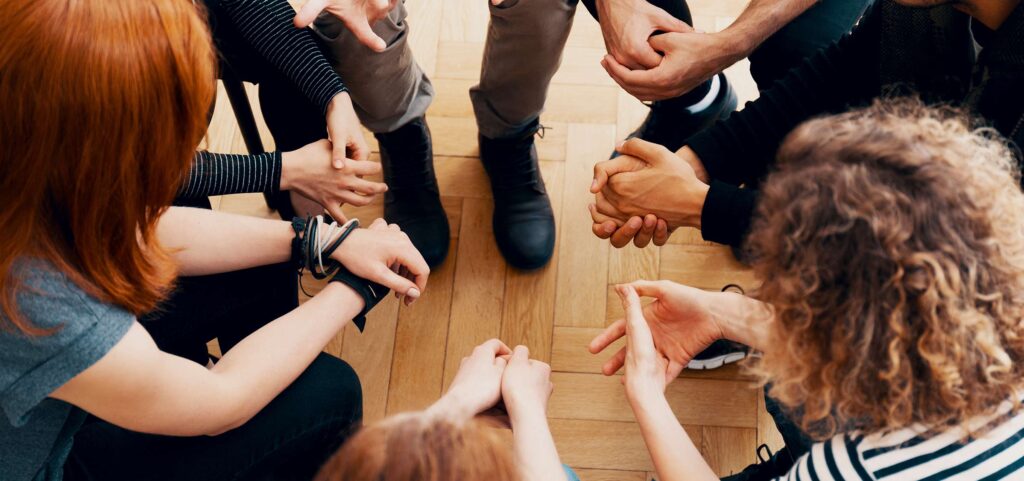 High angle view of hands of people in group therapy, talking and supporting each other