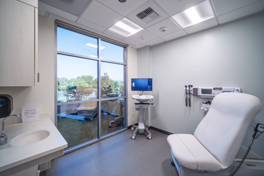 Room with a bed and a wash basin and a computer overlooking a scenic view.