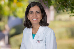 Dr. Cynthia Cherfane smiles while wearing a white medical coat.