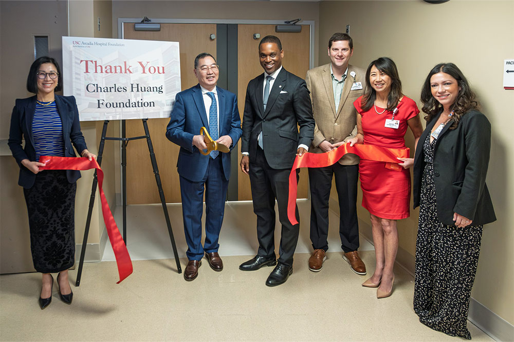 Three women and three men smiling at a ribbon cutting.