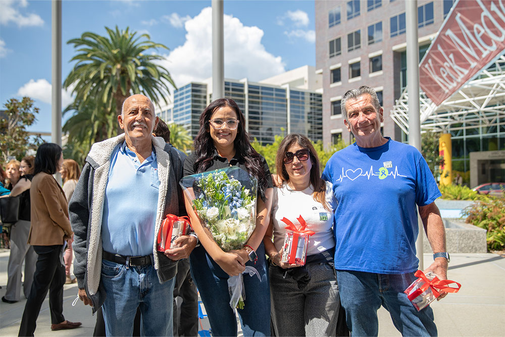 Two older men and two younger women pose in front of Keck Hospital of USC