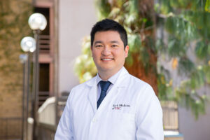 Dr. Tatsuhiro Fujii stands outside and smiles.