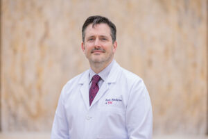 Dr. Mark Sturdevant smiles while wearing a white medical coat.
