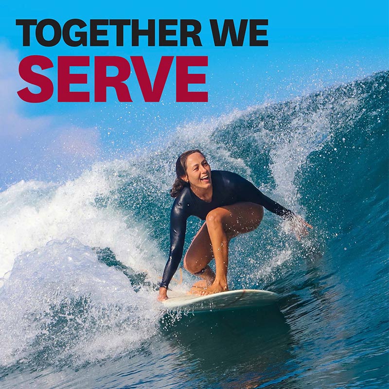 A woman surfing through a barrel of a large ocean wave.
