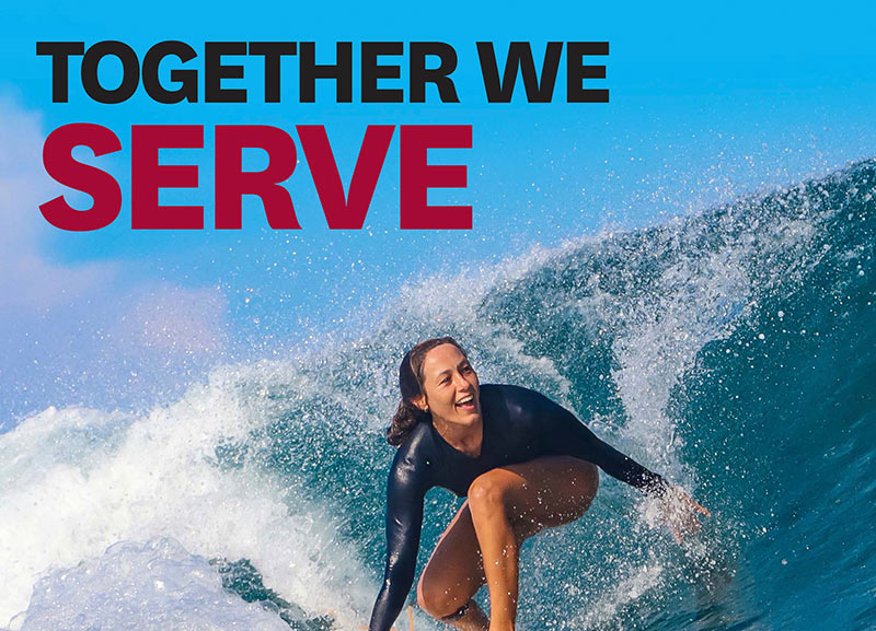 A woman surfing through a barrel of a large ocean wave.