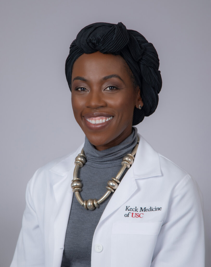 Elodi Dielubanza, MD, smiles for a portrait in a white medical coat.
