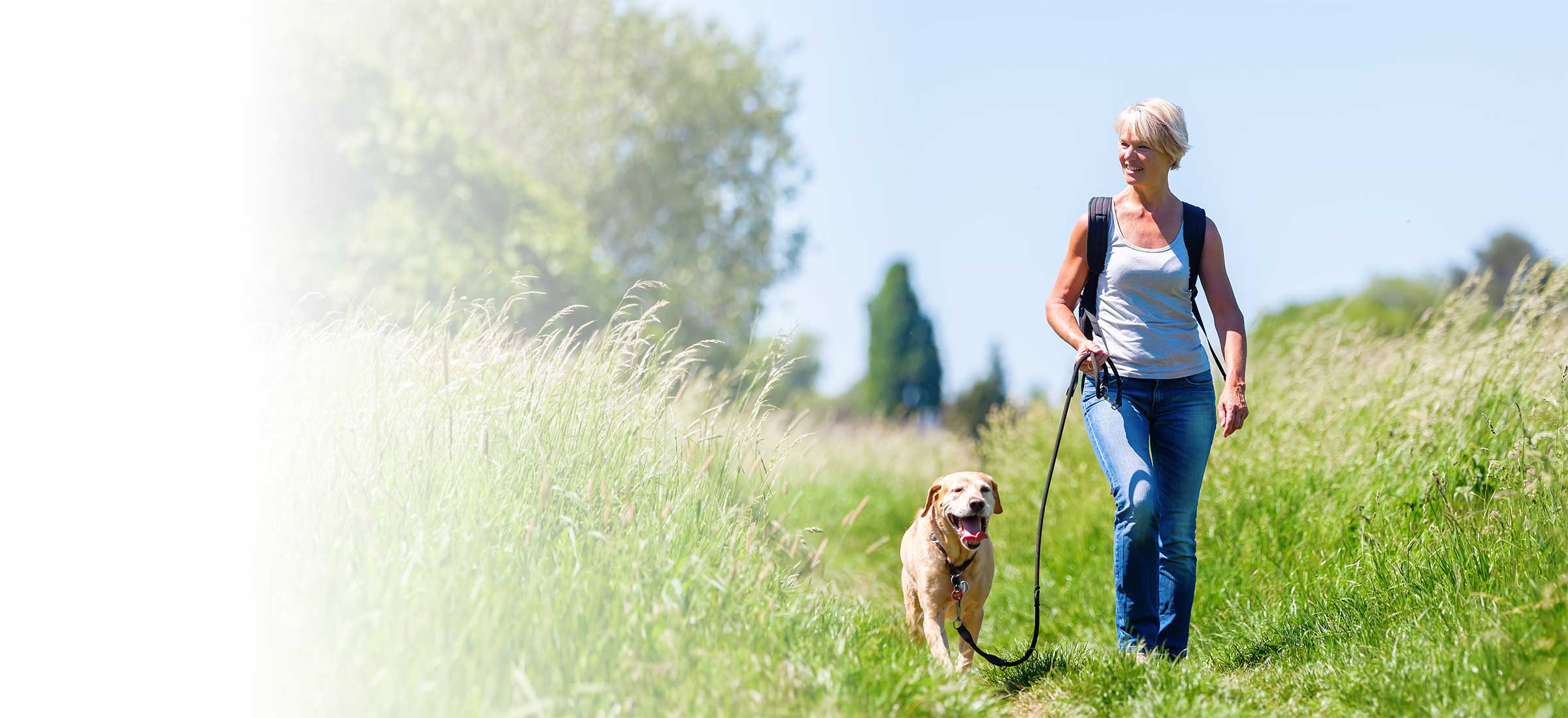 A woman with a heart valve problem walks her dog in a field.