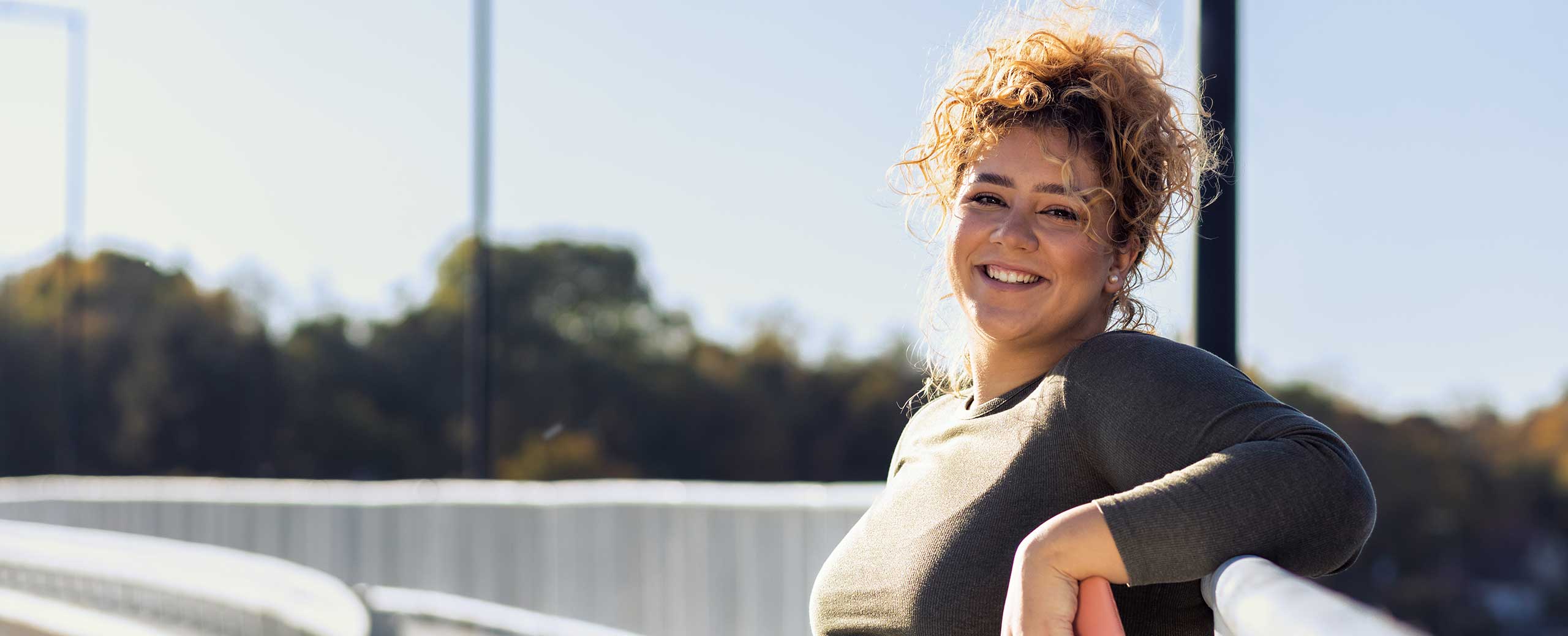 A woman smiles outside on a trail.