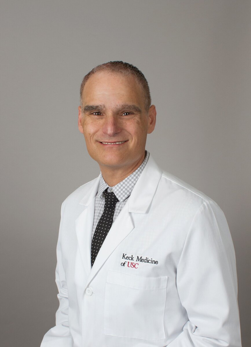 Dr. Kahn stands in a white medical coat against a grey background